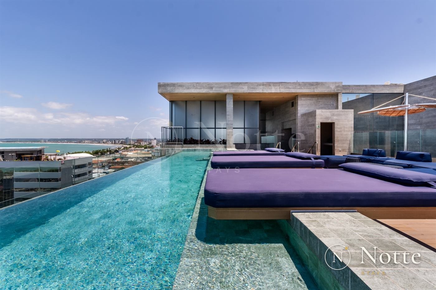 Rooftop do New Time com piscina e espreguiçadeiras de frente para o mar